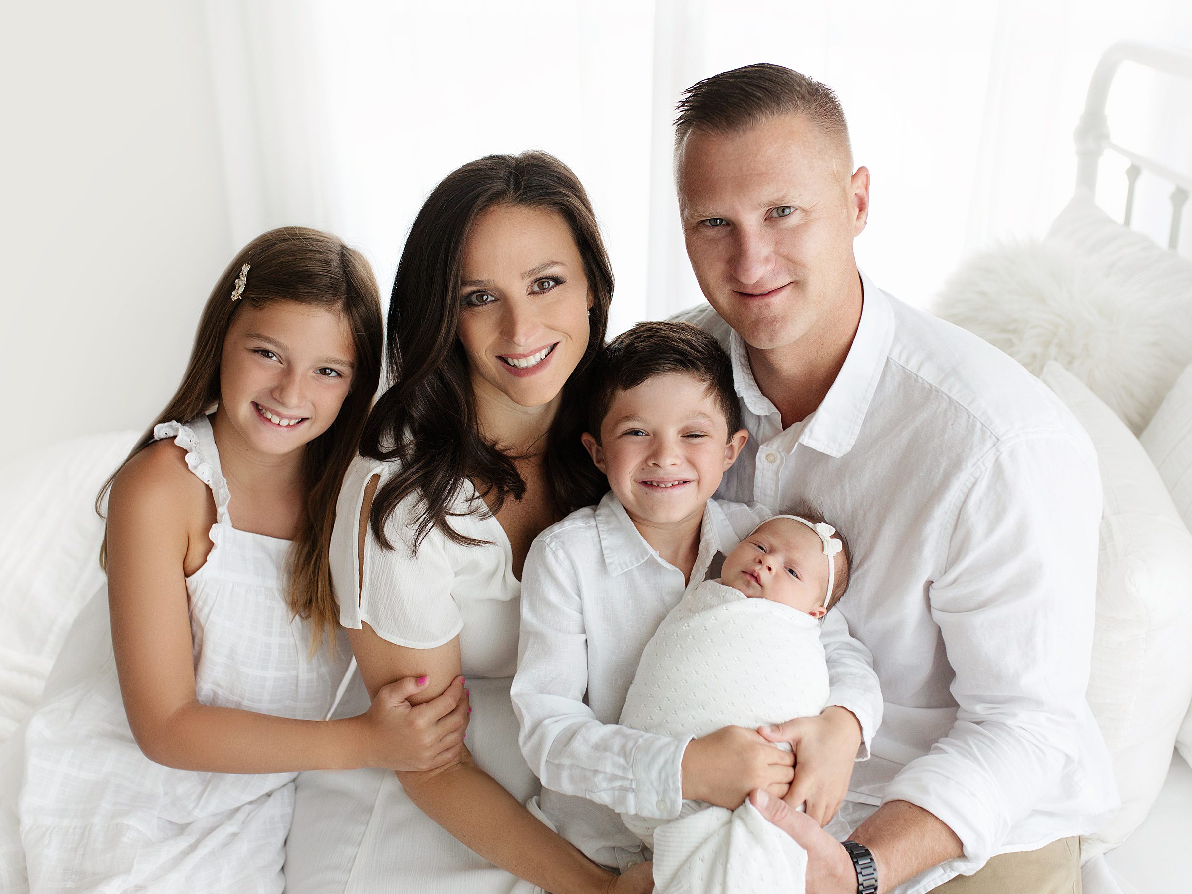 family and newborn baby dressed in all white during photography session in Bentonville Arkansas studio