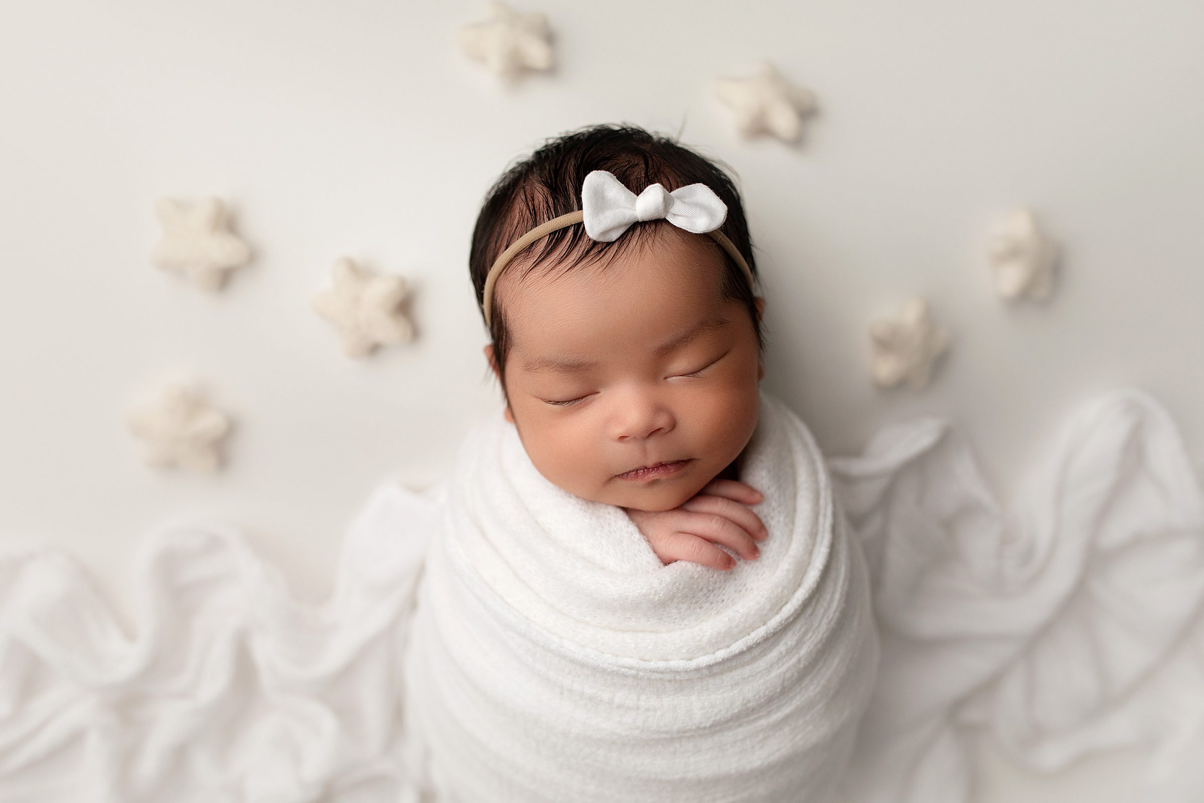 Bentonville Arkansas Newborn Photography Session baby girl neutral swaddled with white felt stars in background